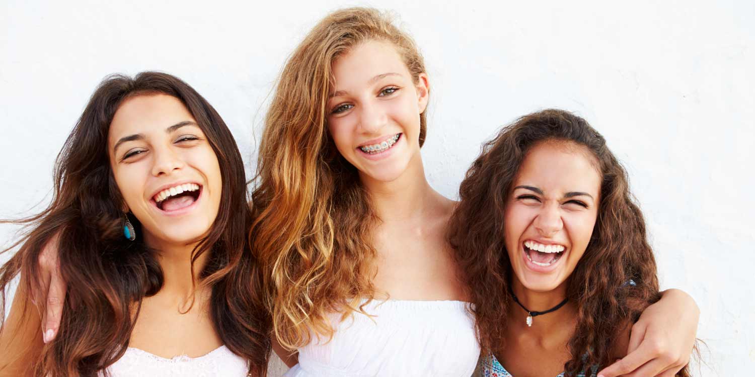 3 teenage girls smile, two without braces and one with braces who keeps her mouth clean