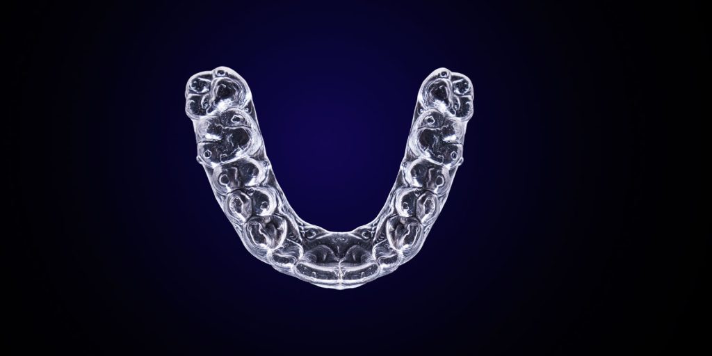 Aerial view of a clear aligner tray against a navy background