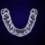 Aerial view of a clear aligner tray against a navy background