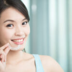 Brunette woman smiles as she holds her Invisalign clear aligners in Weatherford, TX