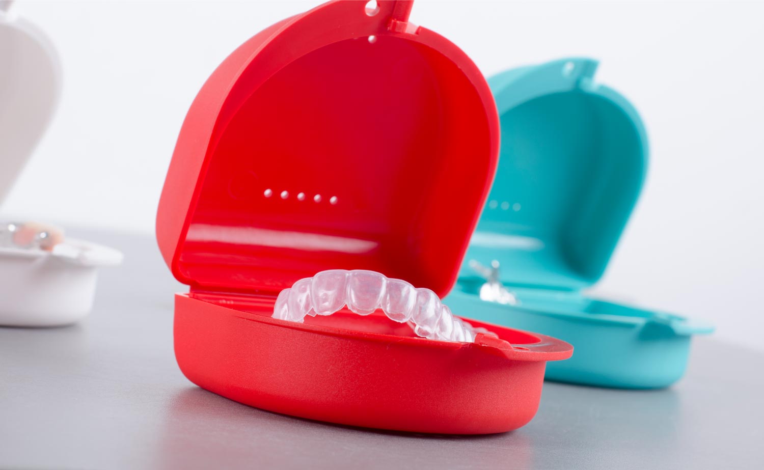 A bright red case showing a clear aligner.