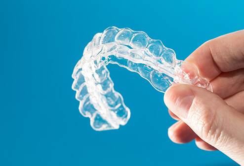 closeup of a person holding a set of clear aligners