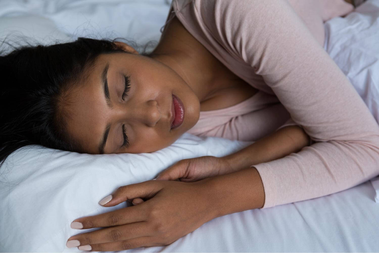 Woman in a pink sweater sleeps with her Invisalign in at night to total 20-22 hours a day of wear