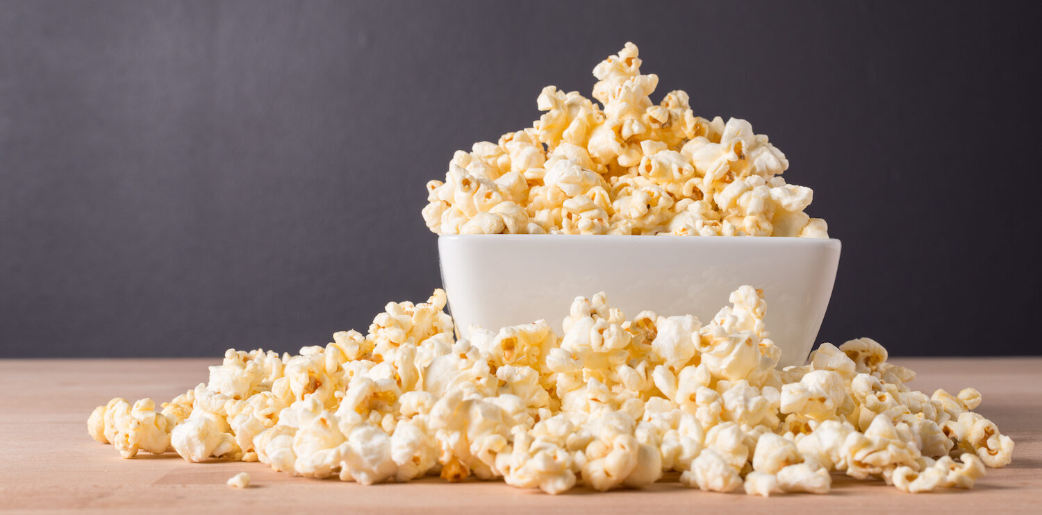 Popcorn, which is a food to avoid with braces, in a white bowl against a gray wall