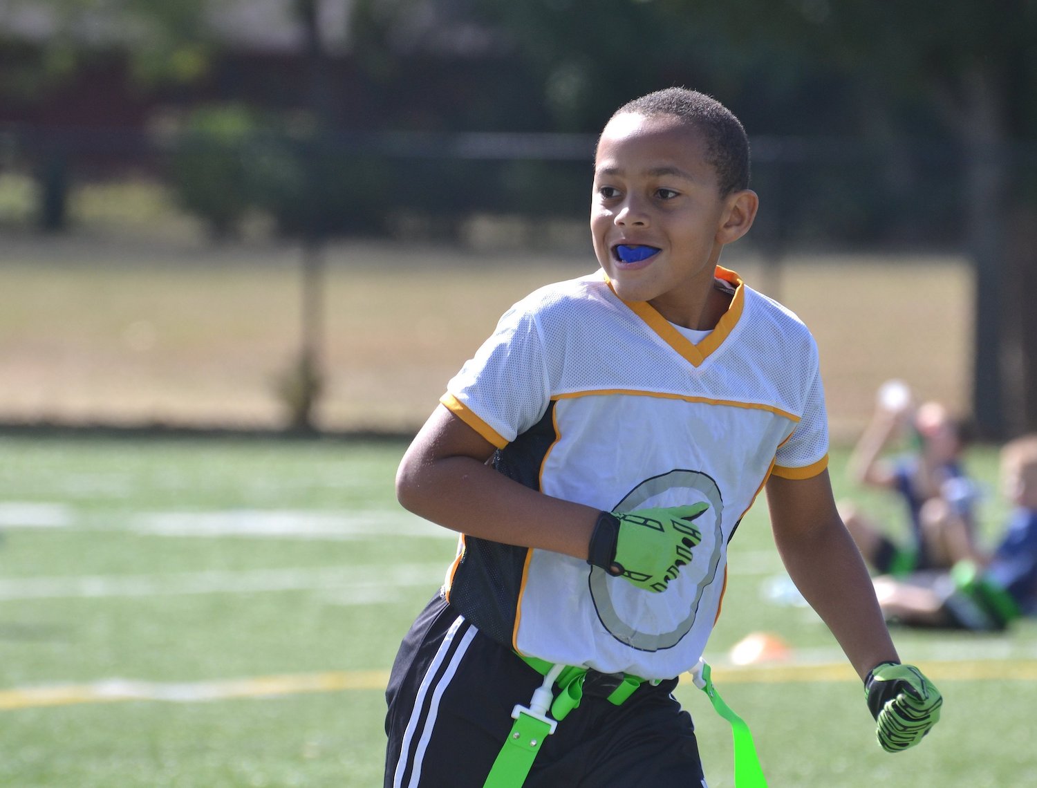 Young Black boy playing flat football while wearing an athletic mouthguard to protect his smile.