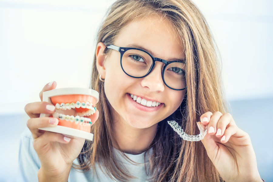 orthodontic treatment options, Dental invisible braces or silicone trainer in the hands of a young smiling girl. Orthodontic concept - Invisalign.