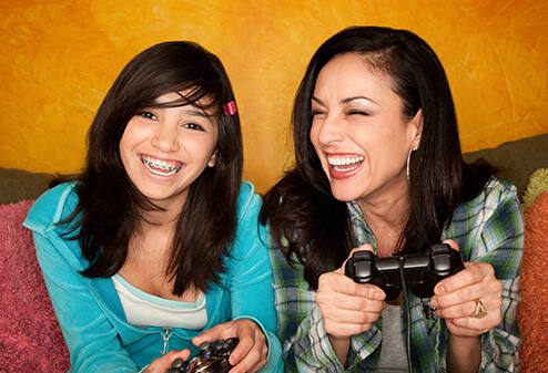 two girls, one of whom is wearing braces, playing video games together