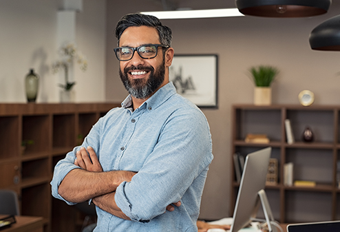 man with glasses smiling with his arms crossed